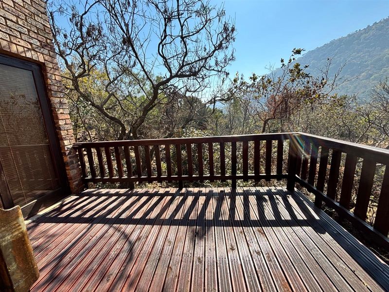 An elevated timber deck balcony featuring a wooden balustrade, brick exterior wall, and scenic natural views.