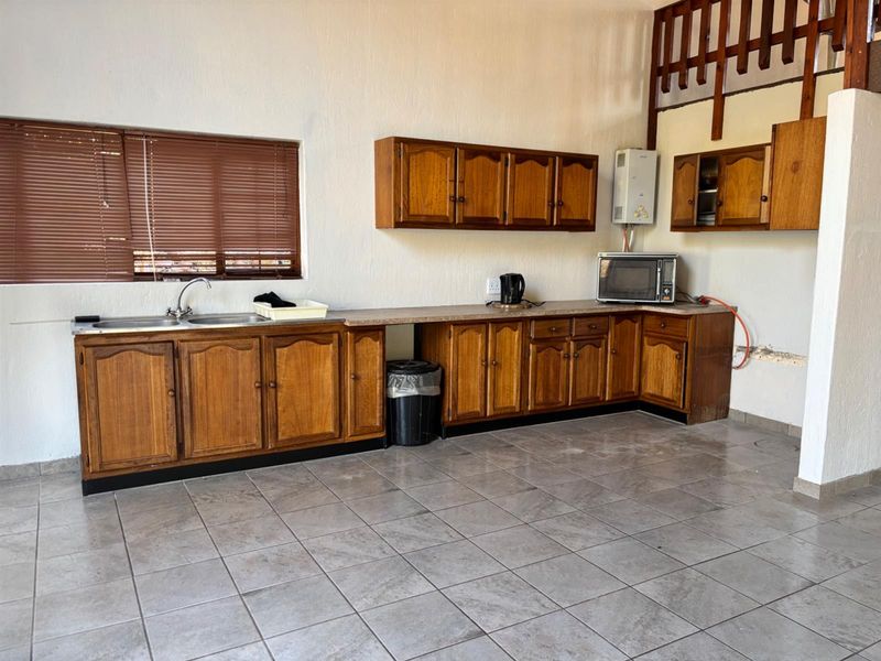 A functional kitchen featuring wooden cabinetry, tiled flooring, and a double sink, offering potential for modernization and aesthetic updates.