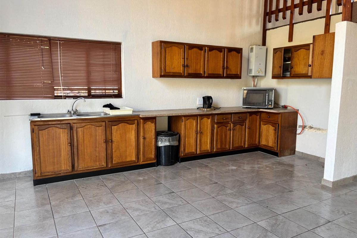 A functional kitchen featuring wooden cabinetry, tiled flooring, and a double sink, offering potential for modernization and aesthetic updates.