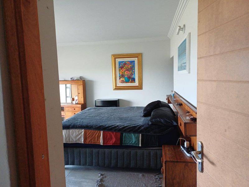 A bedroom featuring a built-in wooden headboard with integrated shelving and bedside storage, finished with tiled flooring and crown molding.