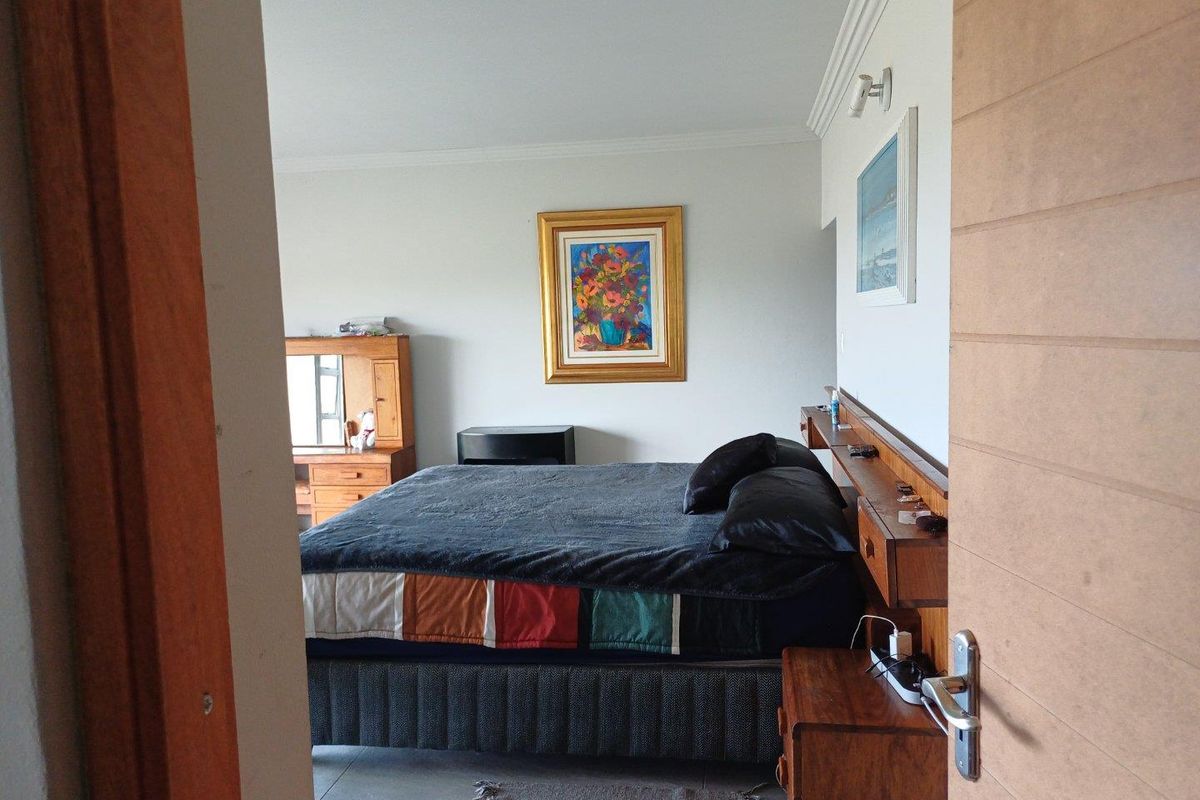 A bedroom featuring a built-in wooden headboard with integrated shelving and bedside storage, finished with tiled flooring and crown molding.