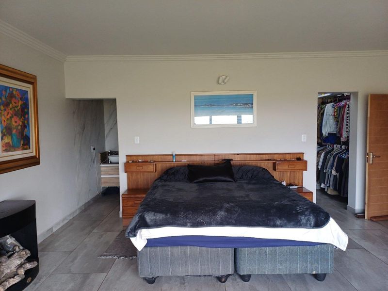 Spacious bedroom featuring a built-in wooden headboard with integrated bedside tables, tiled flooring, and direct access to an en-suite bathroom and walk-in closet.