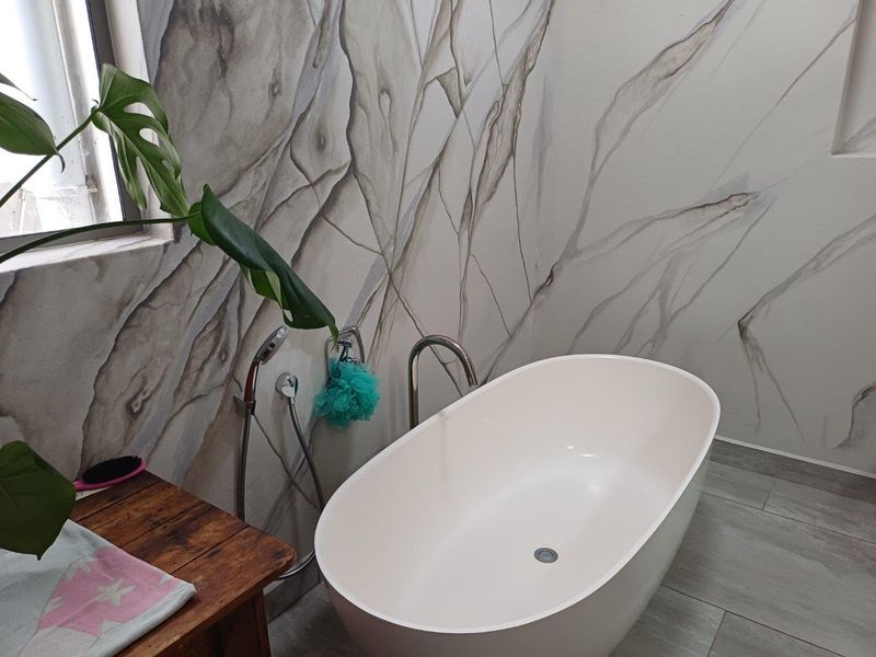 Modern bathroom featuring a freestanding oval bathtub, contemporary chrome fixtures, and large-format marble-effect wall tiling.