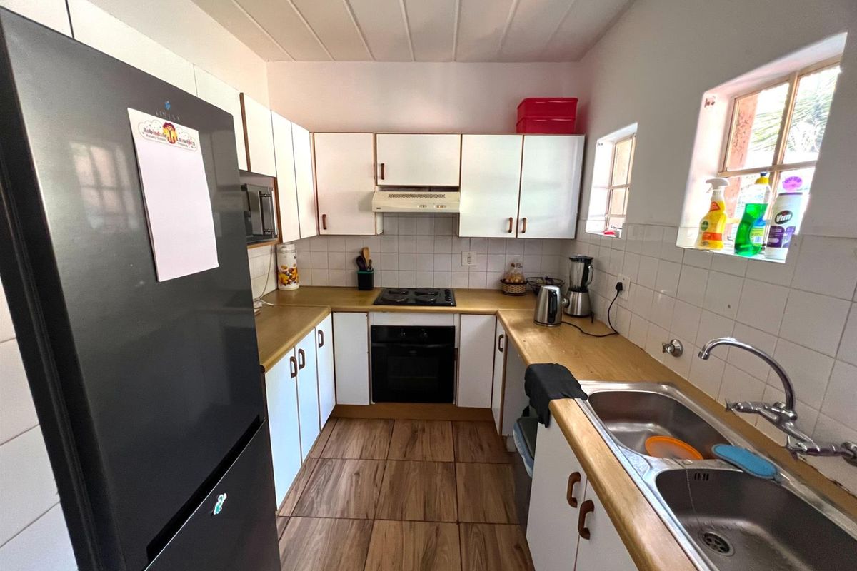 A functional kitchen featuring white cabinetry, wood-look countertops, a built-in oven with hob, and a double stainless steel sink.