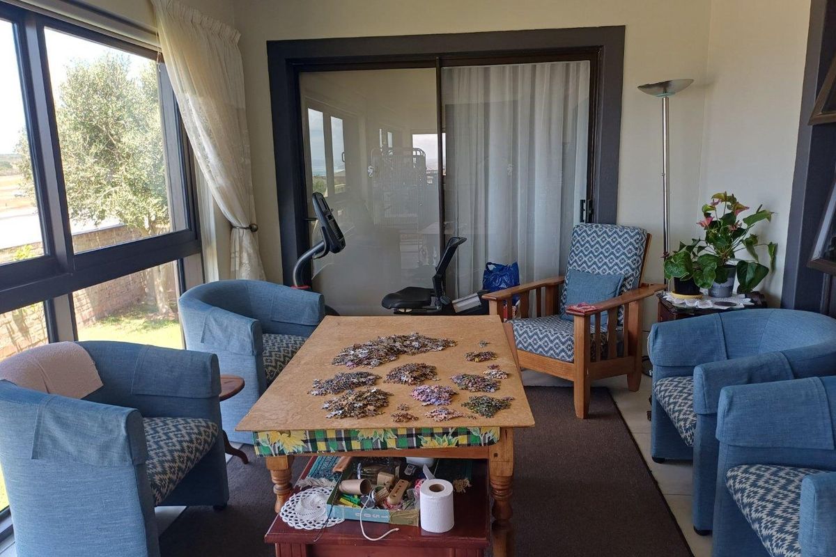 A sunlit living room featuring large windows and sliding glass doors that provide ample natural light and access to the outdoors.