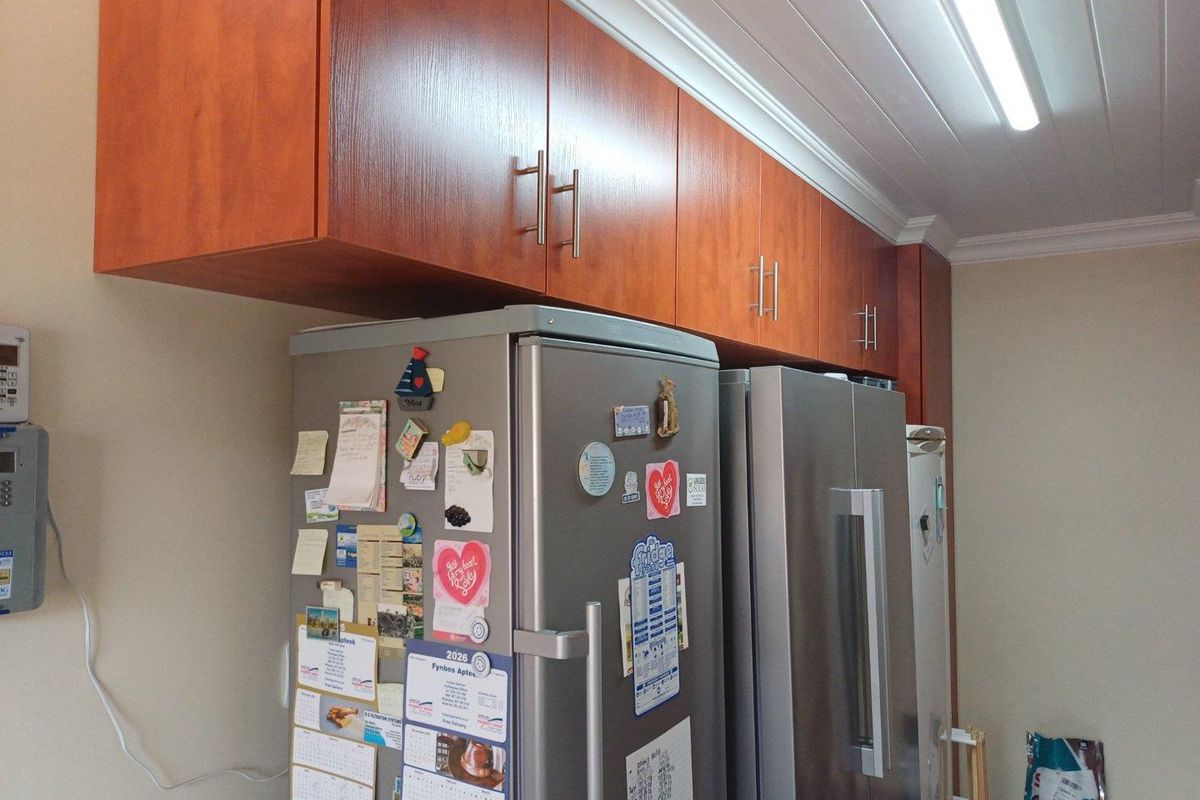 A kitchen area featuring wood-finish upper cabinetry and a panelled ceiling with integrated lighting.