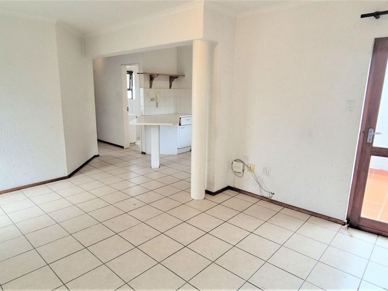 An empty open-plan living area featuring tiled floors, a structural column, and direct access to an outdoor patio space.