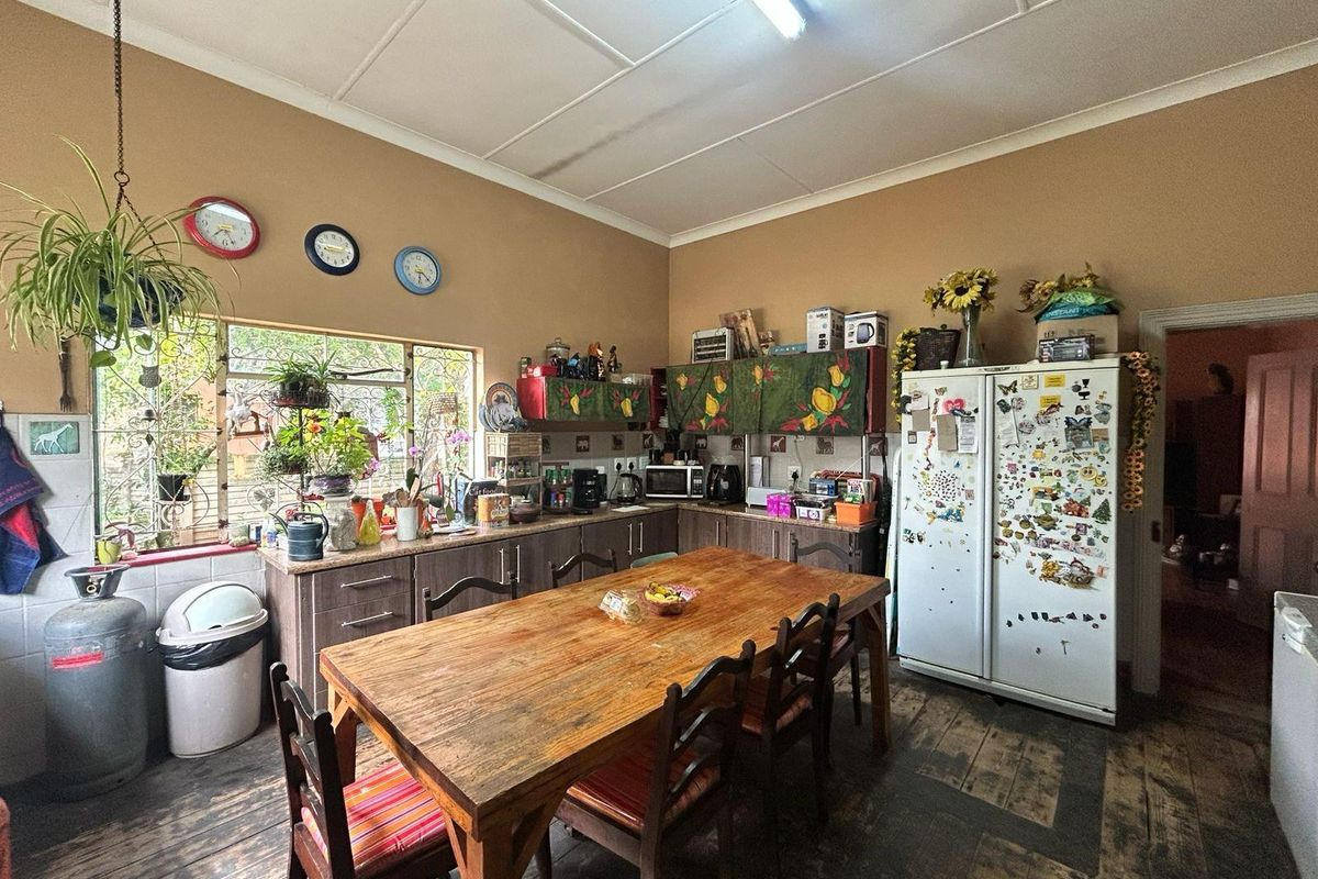 Spacious kitchen featuring timber flooring, built-in cabinetry, and a large dining area, offering a functional layout with potential for modernization.