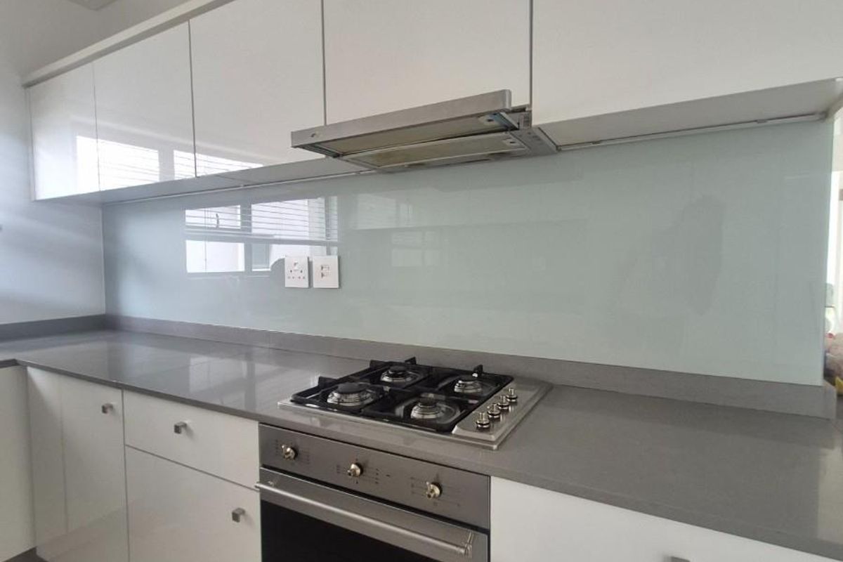 Modern kitchen featuring white cabinetry, stone countertops, a glass splashback, and integrated stainless steel oven and gas hob.