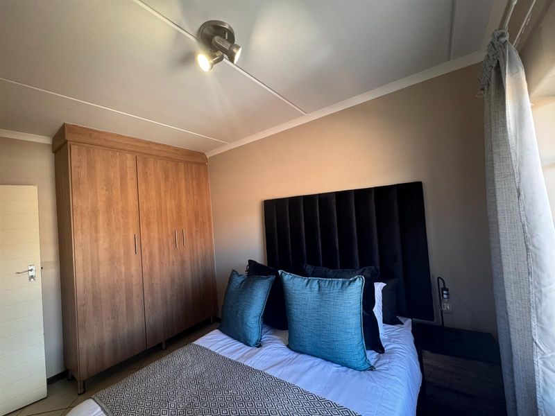 A well-maintained bedroom featuring a large built-in wooden wardrobe and modern ceiling spotlighting, offering a clean and functional living space.