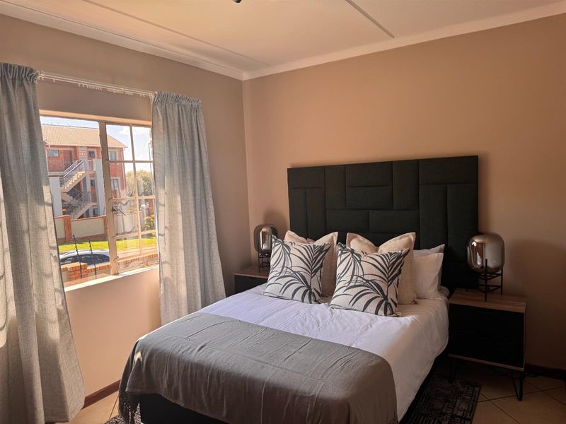 A well-maintained bedroom featuring tiled flooring, a coved ceiling, and a window with security bars, offering a comfortable and functional living space.