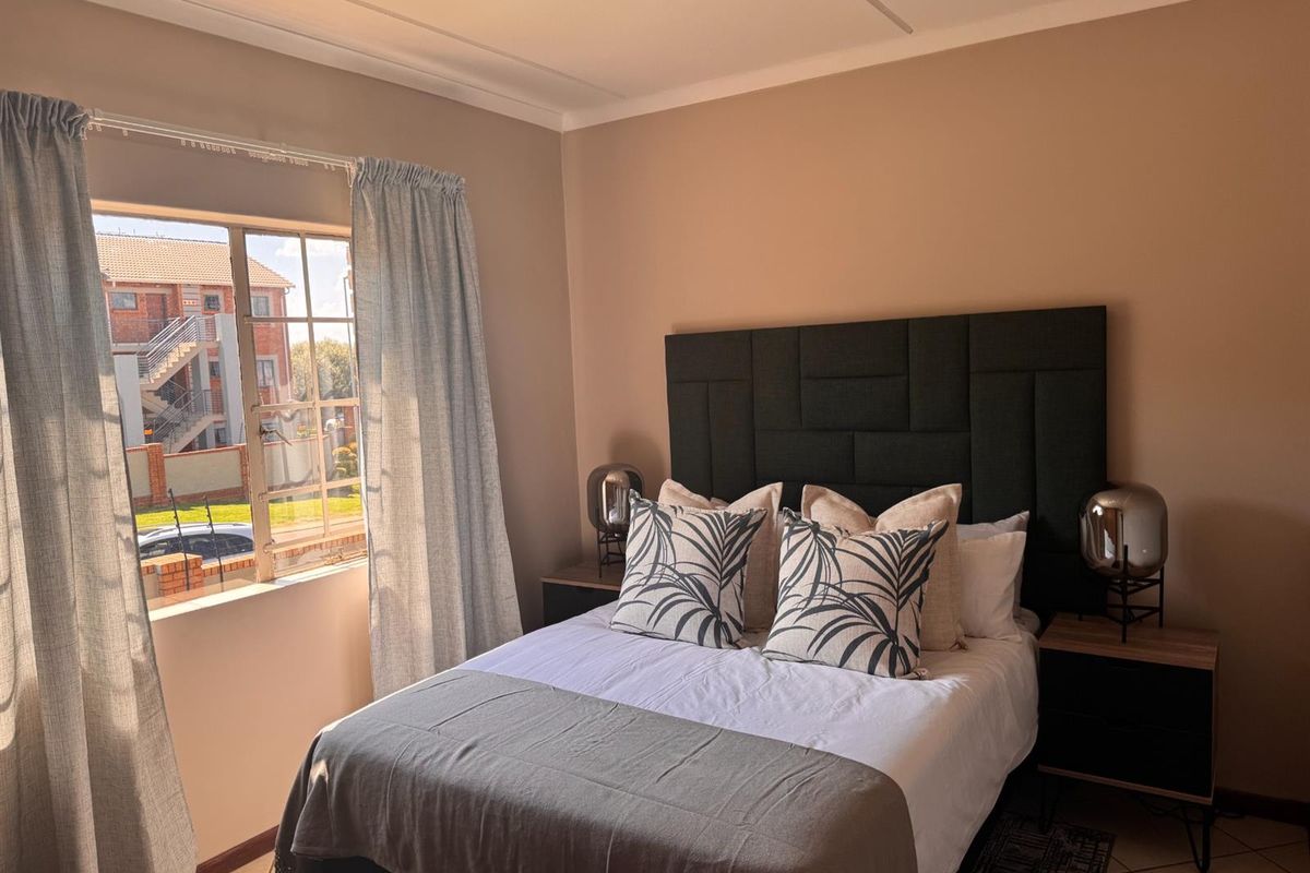 A well-maintained bedroom featuring tiled flooring, a coved ceiling, and a window with security bars, offering a comfortable and functional living space.