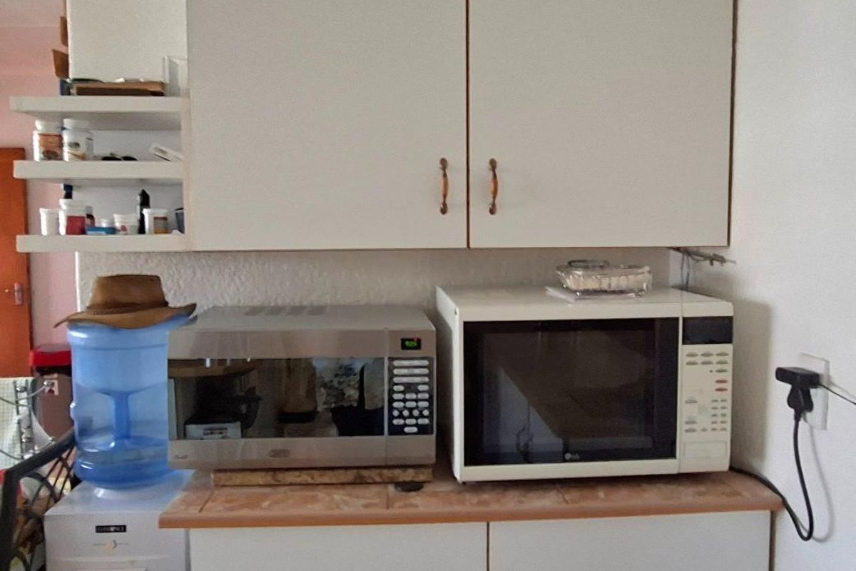 A kitchen prep area featuring white cabinetry, tiled countertops, and open shelving, providing functional storage space.