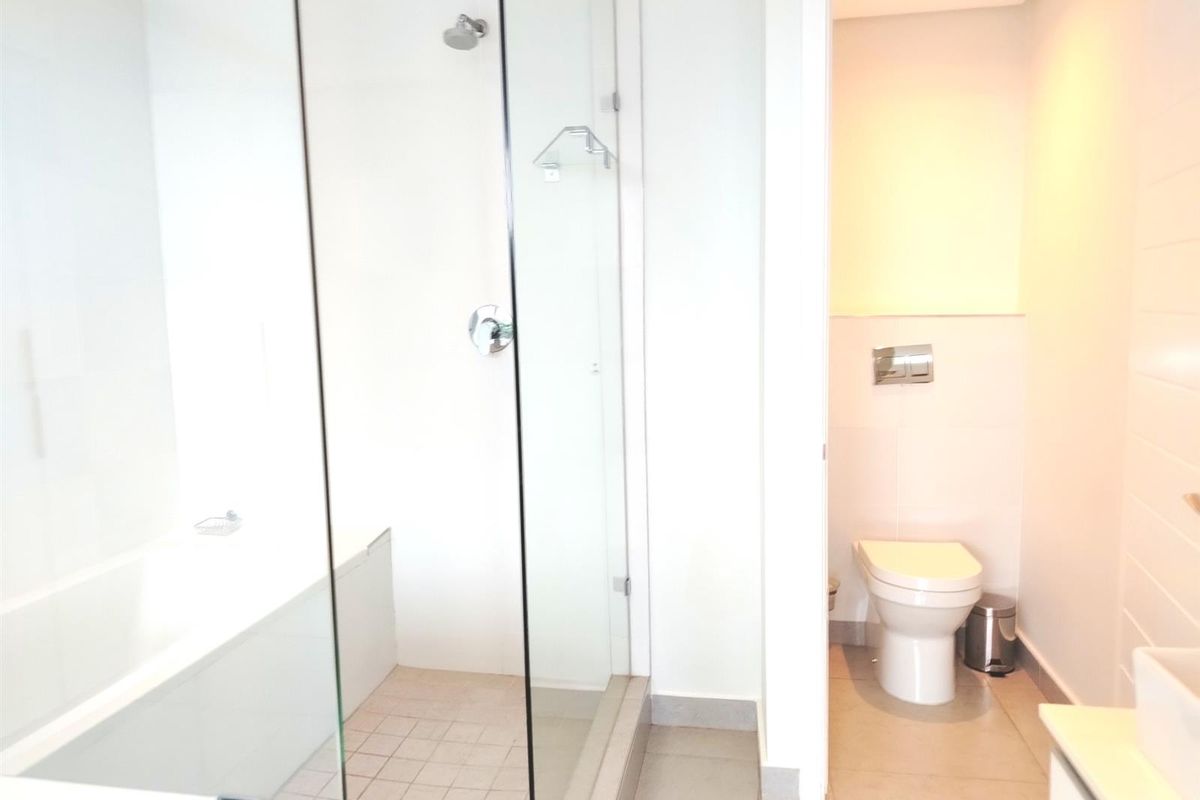 Modern bathroom featuring a glass-enclosed shower, a separate bathtub, and a wall-mounted toilet with a concealed cistern.