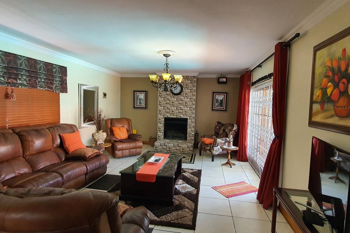 A comfortable living room featuring a stone-clad fireplace, tiled flooring, and large sliding doors leading to an outdoor area.