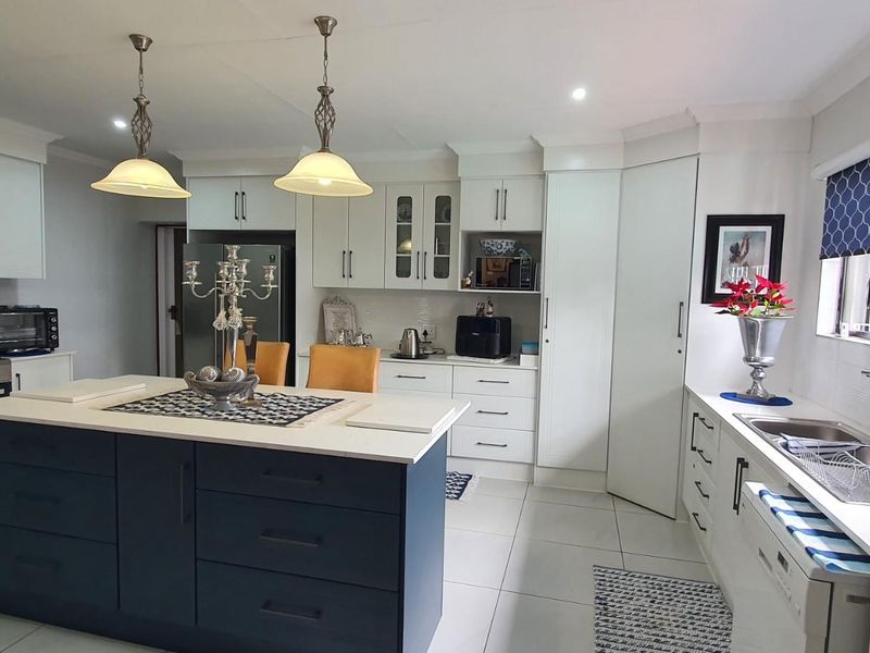 Modern kitchen featuring a central island, white cabinetry, stainless steel gas stove with extractor fan, and tiled flooring.