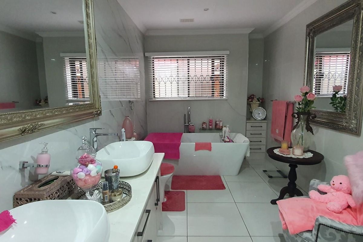 Modern bathroom featuring a double vanity with vessel sinks, a freestanding bathtub, large wall mirrors, and polished floor tiles.