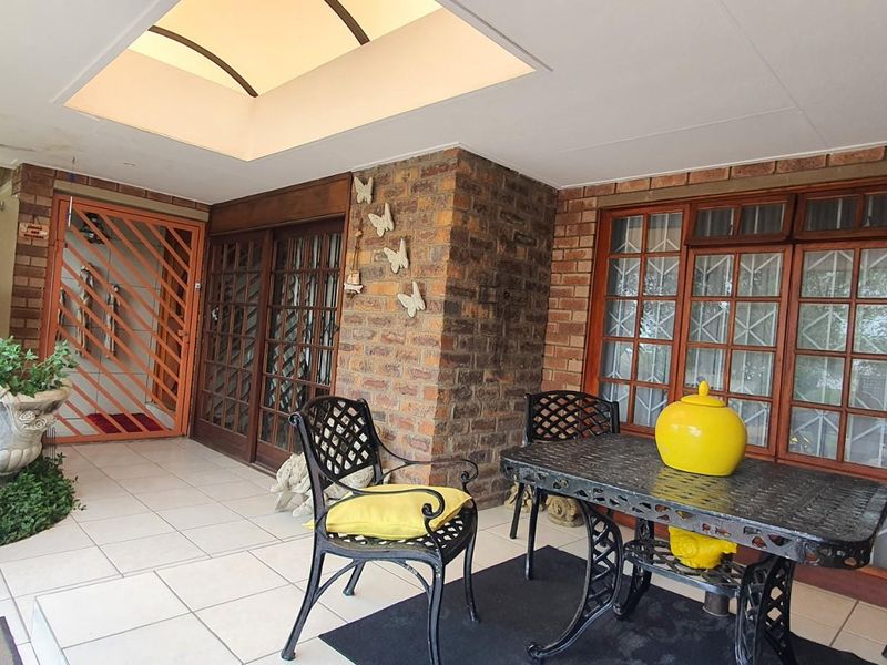 A covered patio area featuring tiled flooring, a skylight, and exposed brickwork, providing a sheltered outdoor space for relaxation.