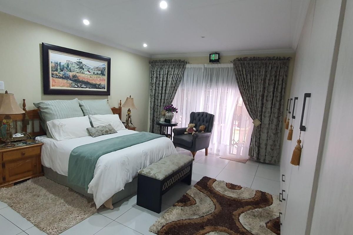 A spacious bedroom featuring tiled flooring, built-in cupboards, and sliding glass doors leading to an outdoor area, with an en-suite bathroom visible.
