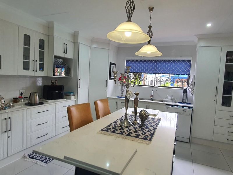 A well-maintained kitchen featuring white cabinetry, a central island with stone countertop, integrated storage, and tiled flooring.