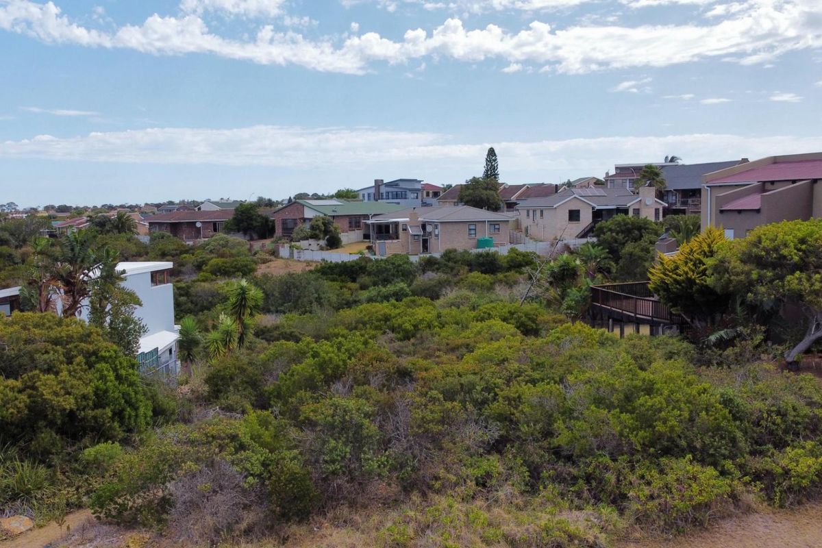 An aerial view of a vacant residential plot covered in dense indigenous vegetation, situated within an established suburban neighborhood.
