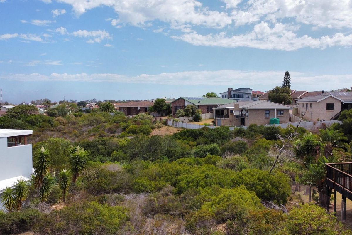 An elevated aerial view of a residential neighborhood featuring natural vegetation, surrounding homes, and a wooden deck structure.