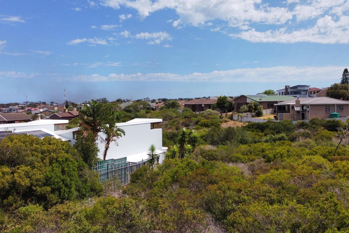 An elevated aerial view of a residential neighborhood featuring dense natural vegetation and surrounding suburban homes.