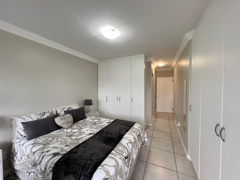 A well-maintained bedroom featuring neutral tiled flooring, built-in cupboards, and classic ceiling cornice detailing.