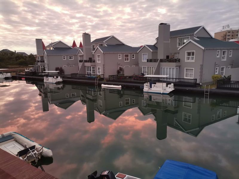 A scenic view of waterfront apartment units featuring private decks, jetties, and direct canal access under a sunset sky.