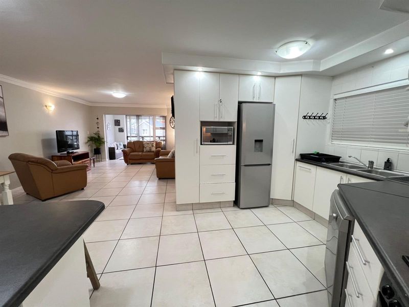 Spacious open-plan kitchen and living area featuring white cabinetry, tiled flooring, and modern recessed lighting, creating a bright and functional living space.