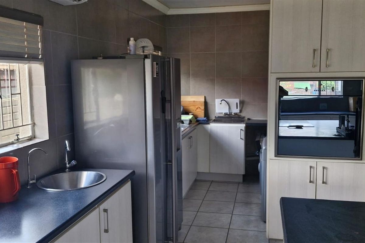 Functional kitchen featuring built-in cabinetry, tiled backsplash, stainless steel sink, and integrated oven with tiled flooring throughout.