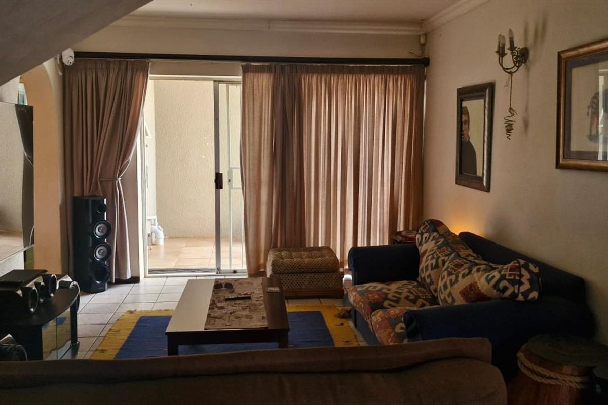 A living room featuring tiled flooring and a sliding glass door providing access to an outdoor patio area.