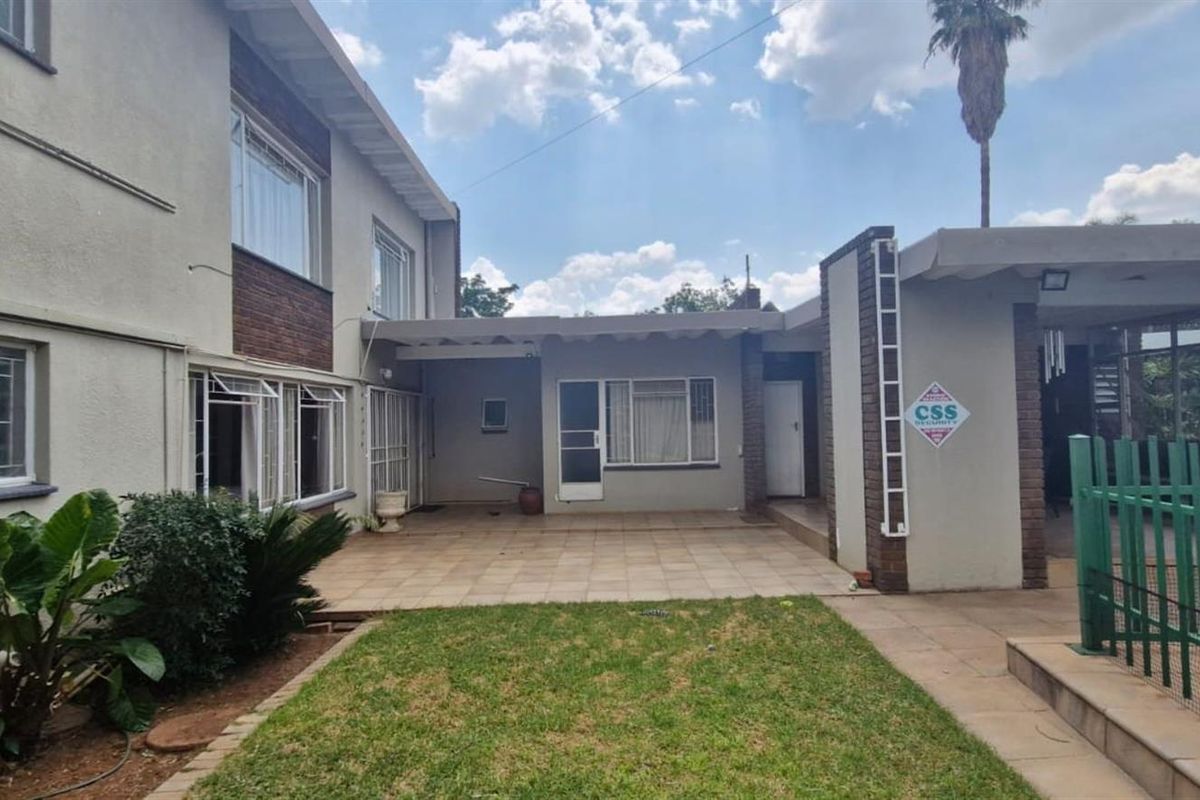 Rear view of the property featuring a paved patio area, lawn, and secure perimeter fencing.