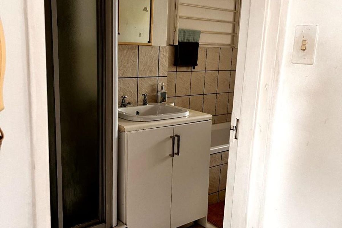 A compact bathroom featuring a shower enclosure, vanity basin, and tiled wall finishes, viewed from the doorway.
