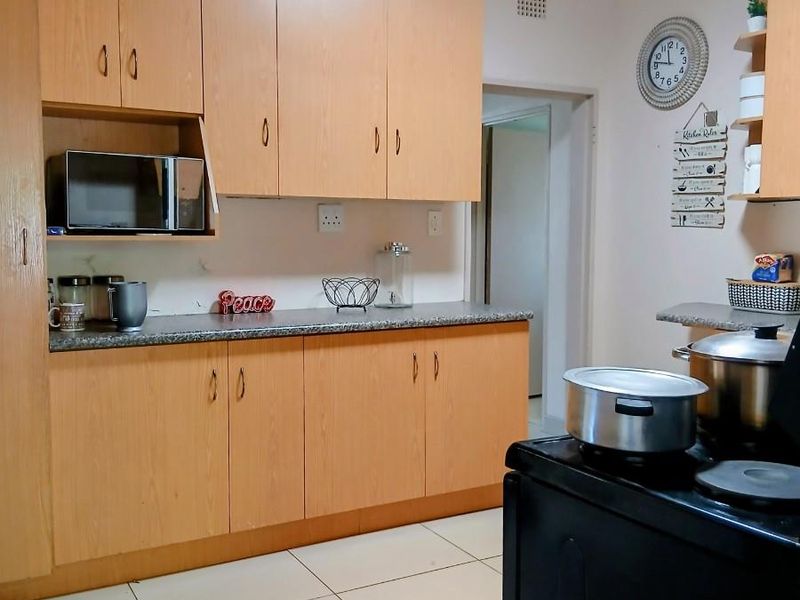 A functional kitchen featuring light wood-tone cabinetry, granite countertops, and neutral ceramic floor tiles, offering a clean and practical workspace.