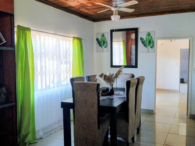 Dining room featuring a timber-clad ceiling, ceiling fan, and tiled flooring, with a view into the adjacent hallway.