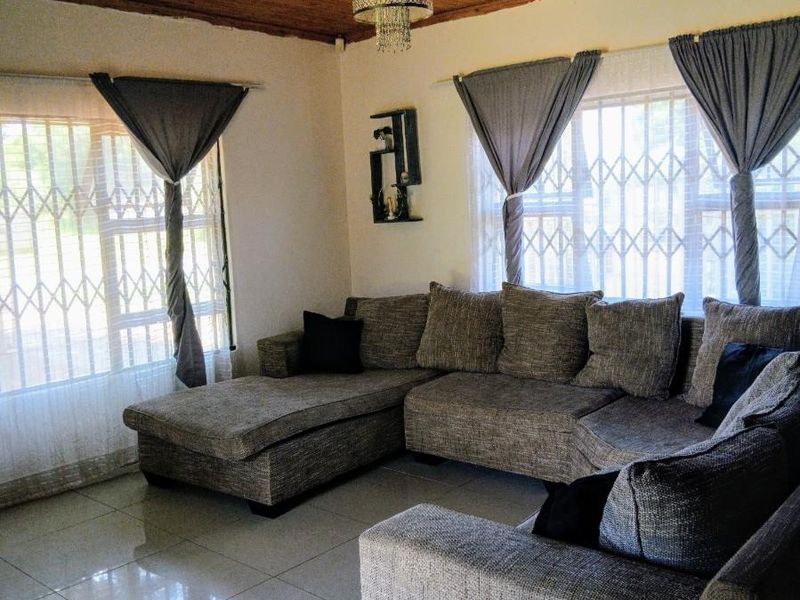 A living room featuring a timber tongue and groove ceiling, polished porcelain floor tiles, and security gates on the windows.
