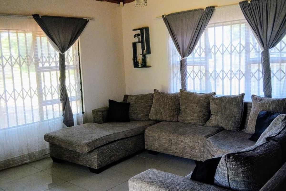 A living room featuring a timber tongue and groove ceiling, polished porcelain floor tiles, and security gates on the windows.