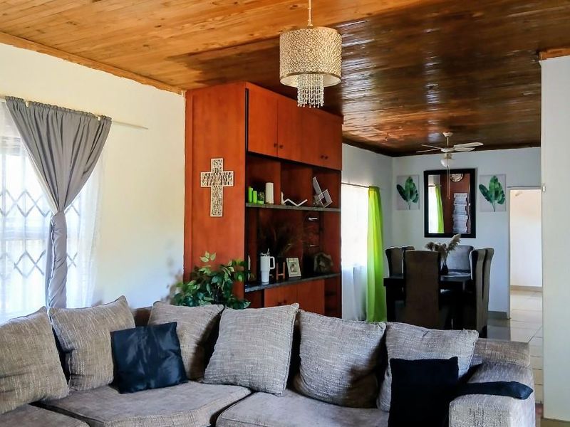 Open plan living and dining area featuring a warm timber tongue and groove ceiling, tiled flooring, and a built-in wooden shelving unit.