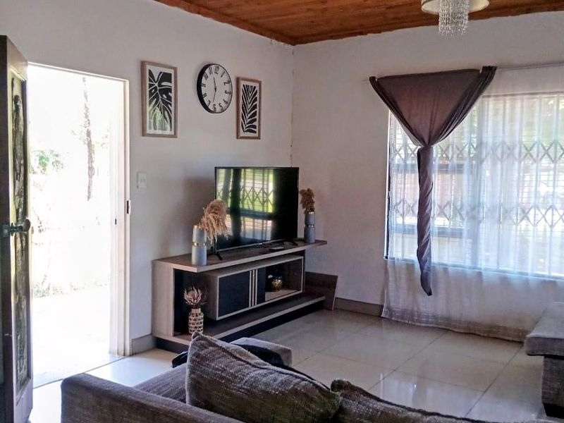 A living room featuring a timber tongue and groove ceiling, tiled flooring, and security bars on the windows, with direct access to the exterior.