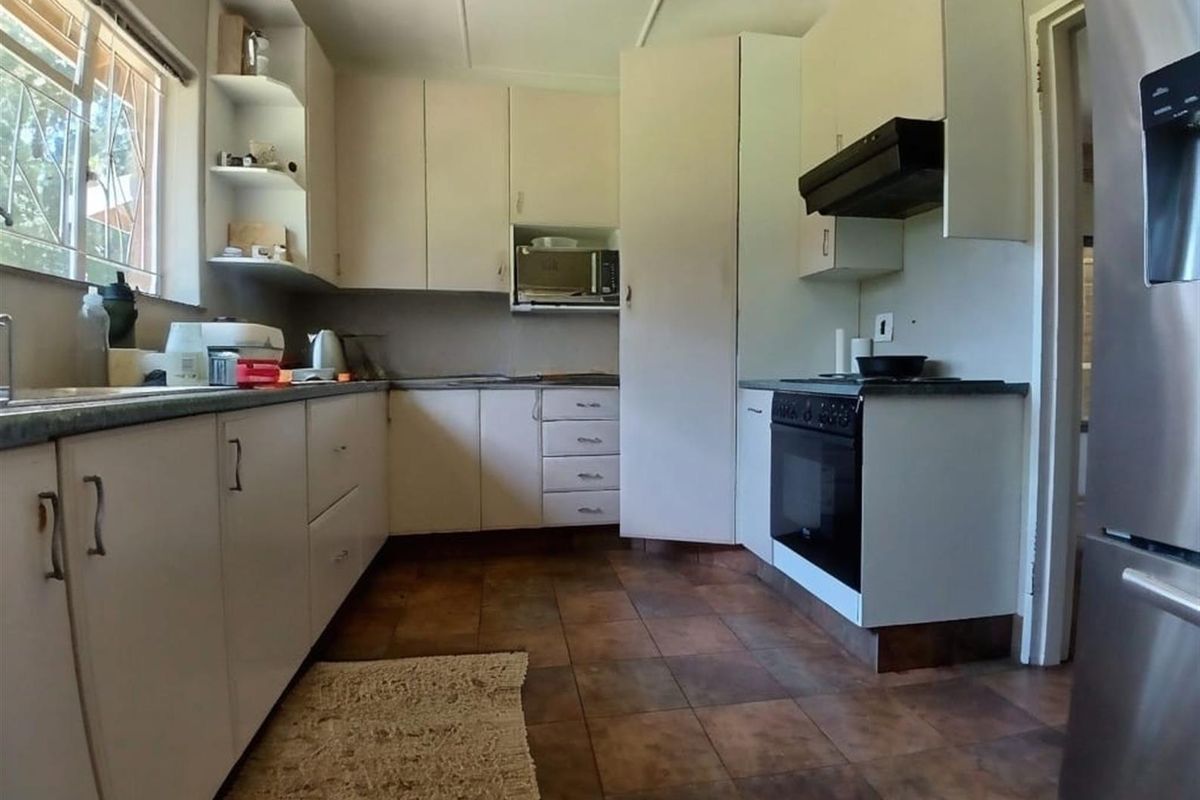 A functional kitchen featuring white cabinetry, dark countertops, a built-in oven with extractor fan, and tiled flooring.