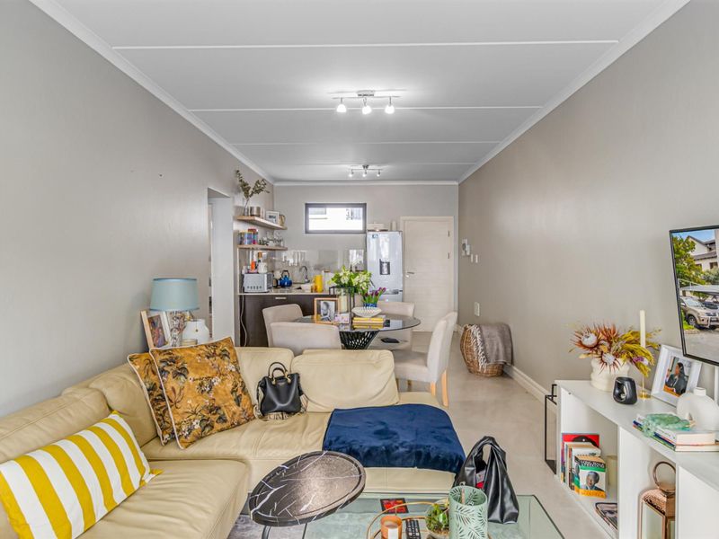 An open-plan living and dining area featuring tiled flooring and a compact kitchen space with built-in cabinetry.
