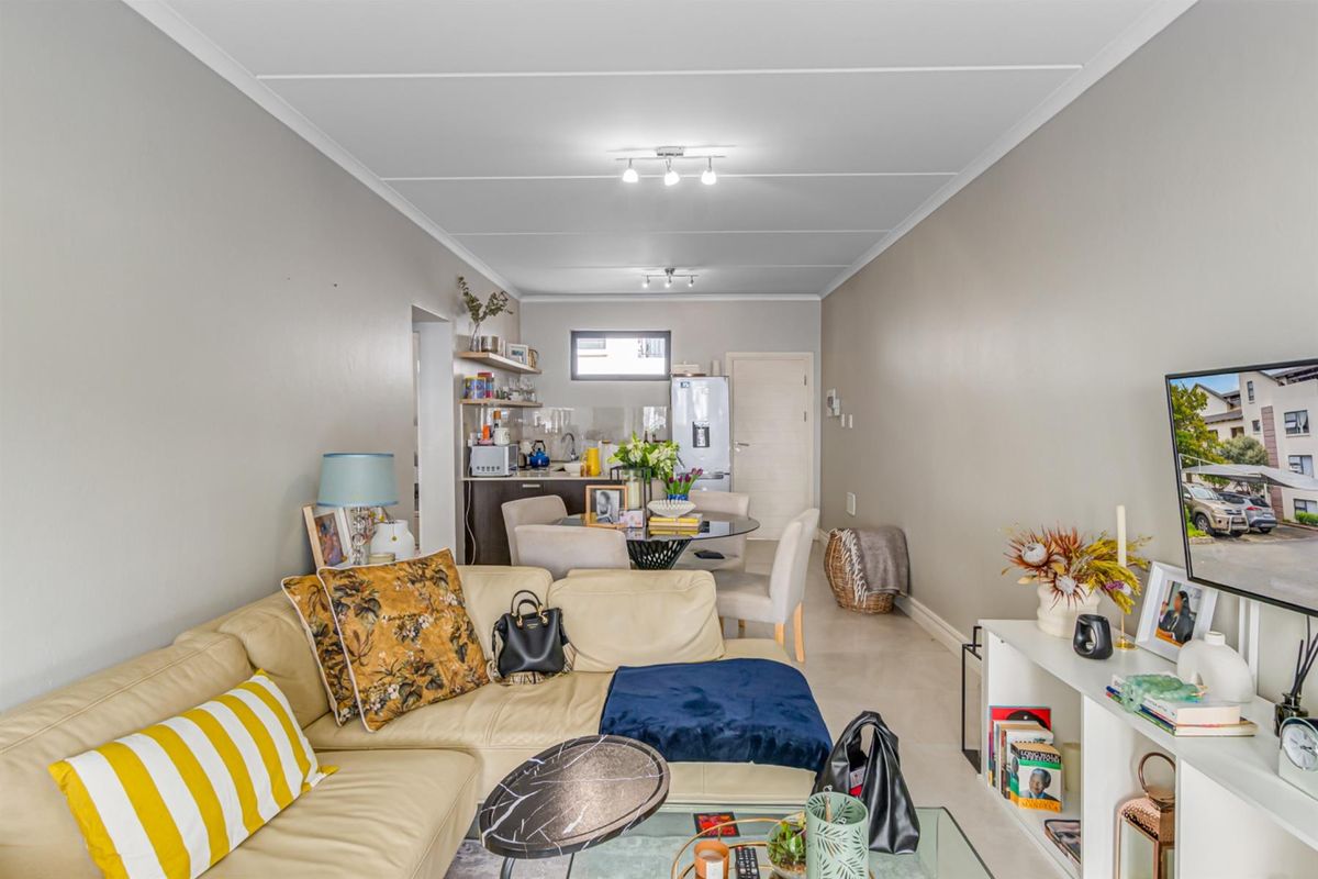 An open-plan living and dining area featuring tiled flooring and a compact kitchen space with built-in cabinetry.