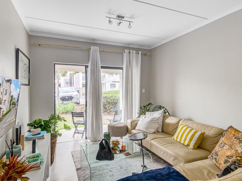 A bright living room featuring tiled flooring and a sliding glass door providing direct access to the exterior patio area.