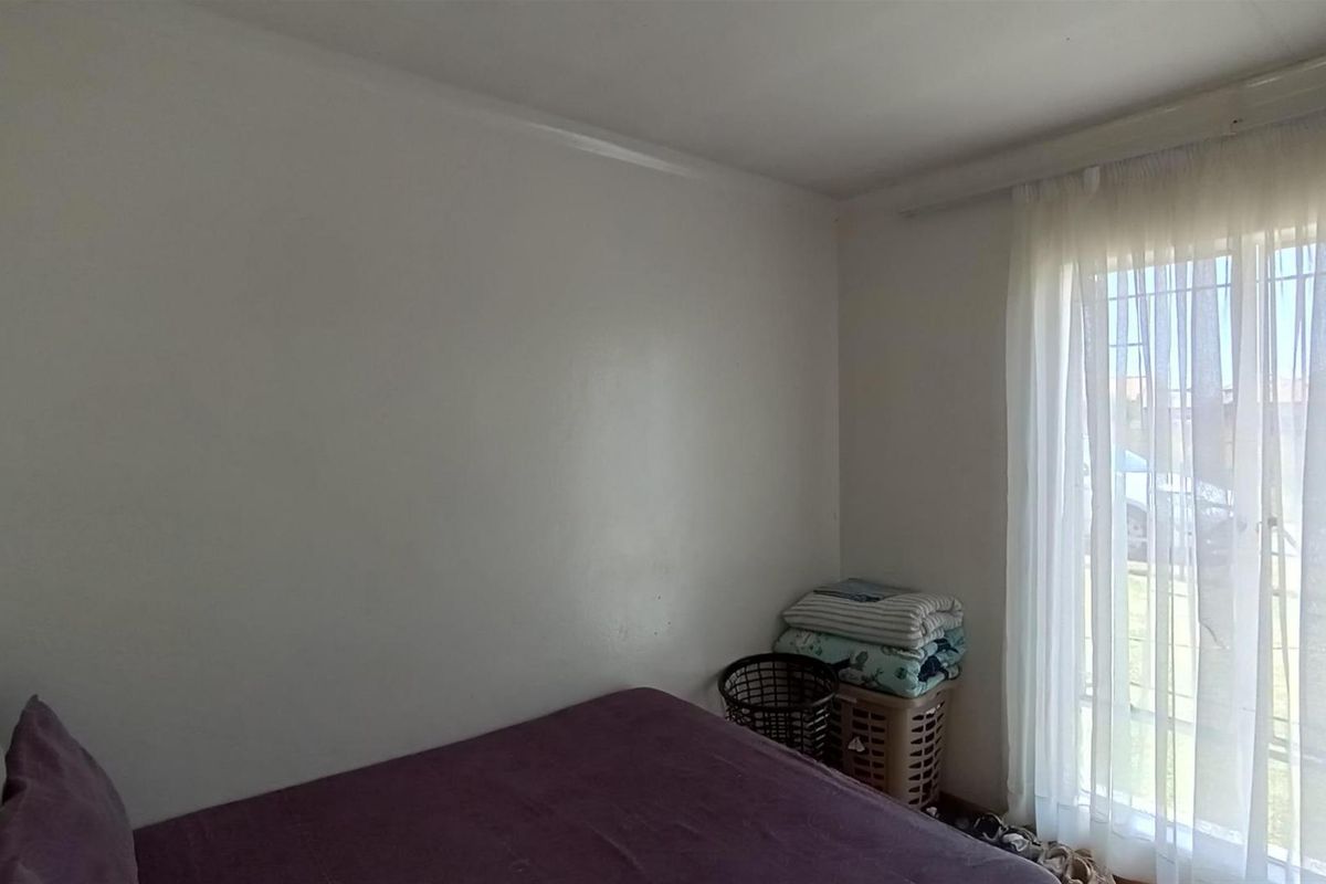 A bedroom featuring a large window with sheer curtains, providing natural light and a view of the exterior.