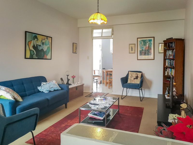 A comfortable living room featuring neutral walls, carpeted flooring, and a transom window leading to an adjacent space.