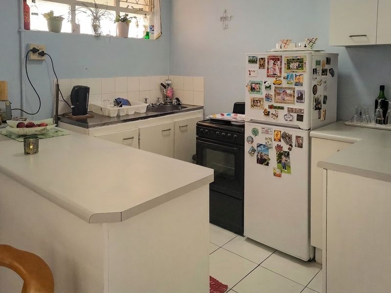 A functional kitchen featuring white cabinetry, laminate countertops, a tiled backsplash, and a freestanding oven with tiled flooring.