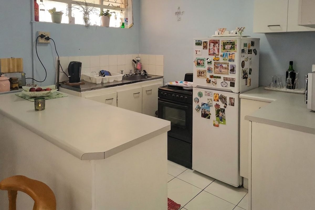 A functional kitchen featuring white cabinetry, laminate countertops, a tiled backsplash, and a freestanding oven with tiled flooring.