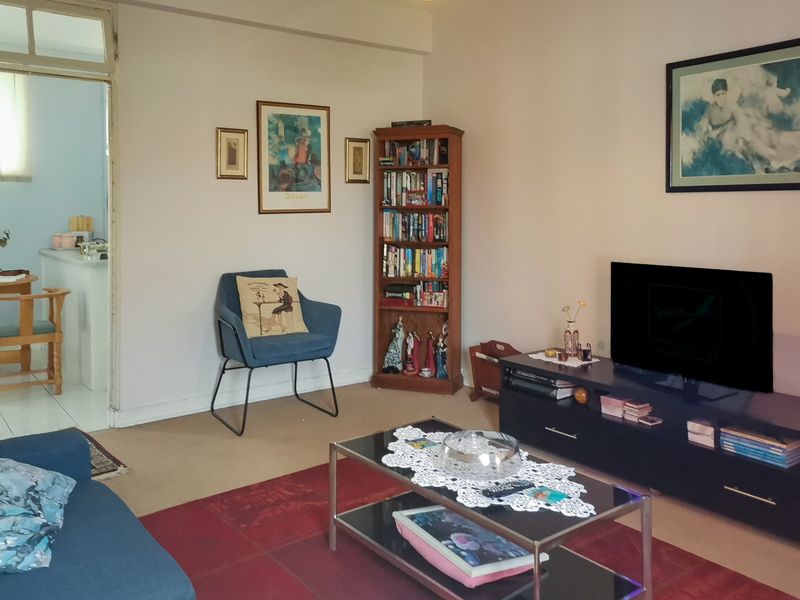 A comfortable living room area with neutral wall tones and carpeted flooring, providing a functional space for relaxation.