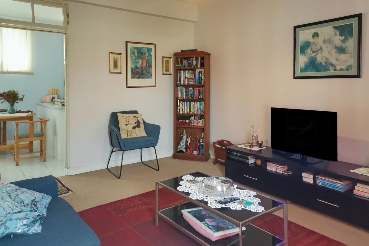 A comfortable living room area with neutral wall tones and carpeted flooring, providing a functional space for relaxation.